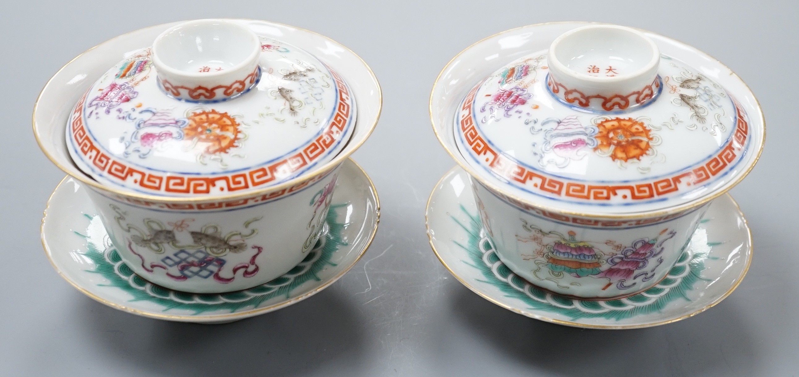A pair of Chinese famille rose bowls, covers and stands painted with the 8 Buddhist emblems, 9cm total height